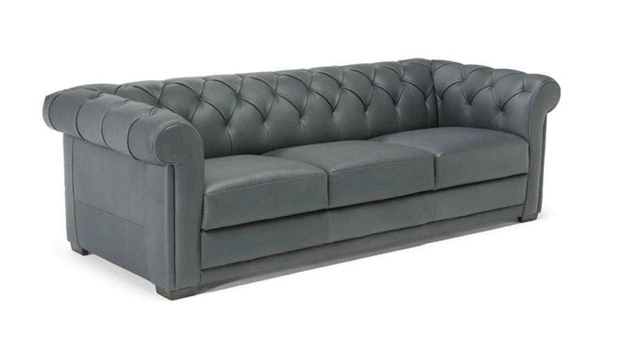 A sleek gray Chesterfield sofa with a tufted backrest and rolled arms, exuding elegance and sophistication. The soft fabric adds a cozy touch.